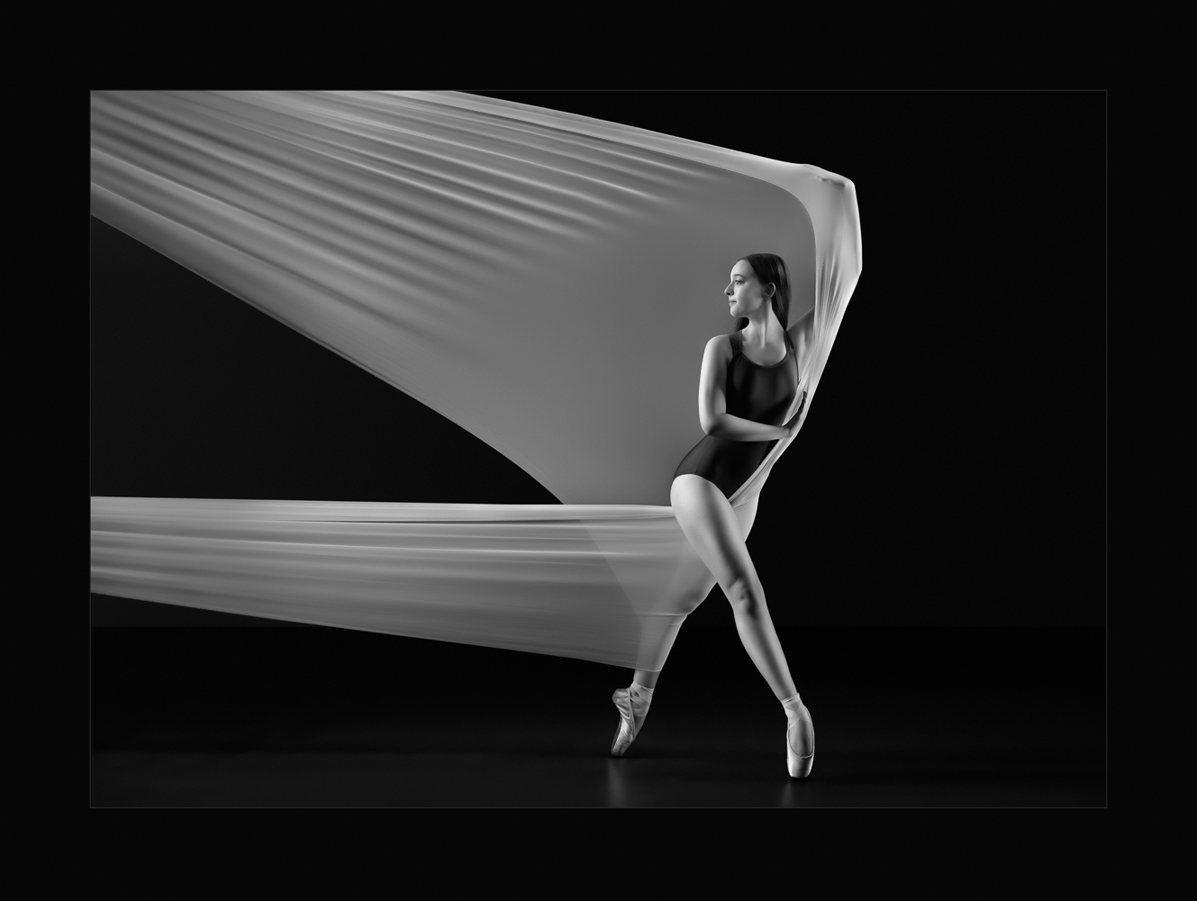 Ballerina pulling against fabric in wide fourth looking back