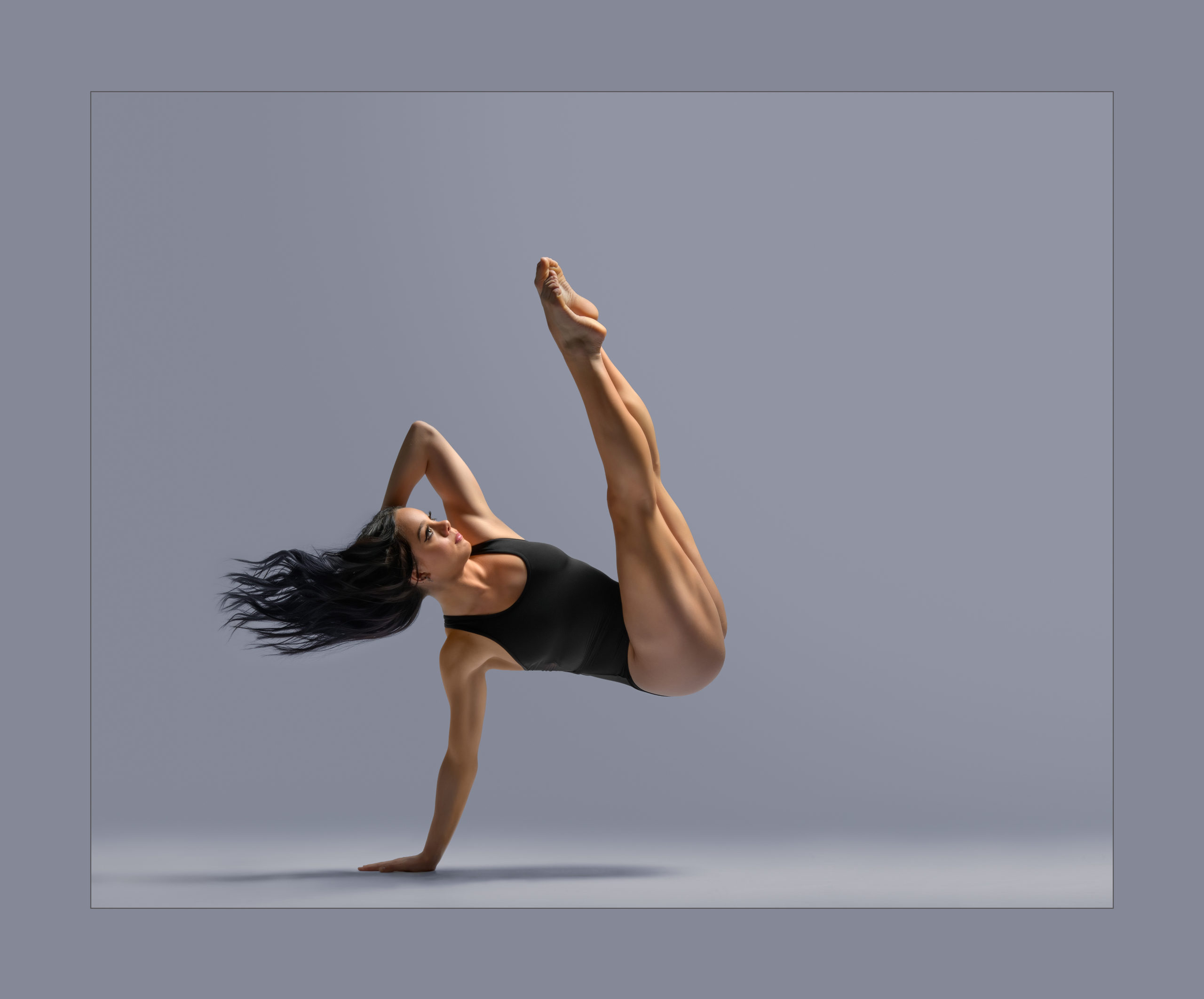 Woman in black leotard pushing up off one hand with other hand behind her head. Legs are kicked up in a pike position.