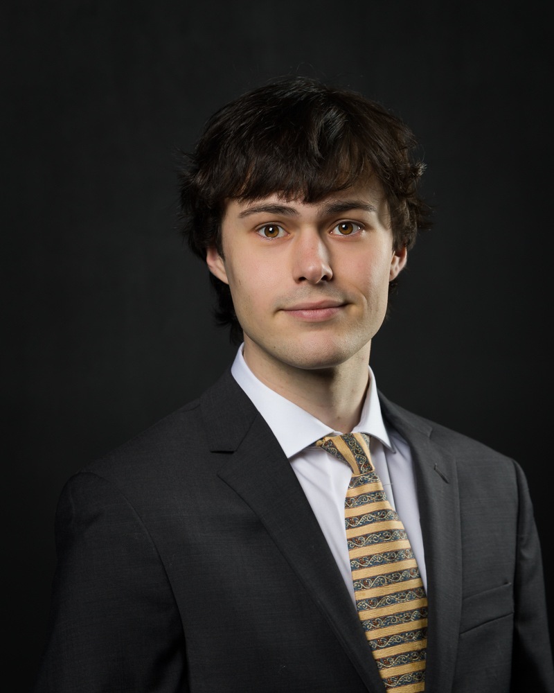 Professional headshot of a young man in business attire.
