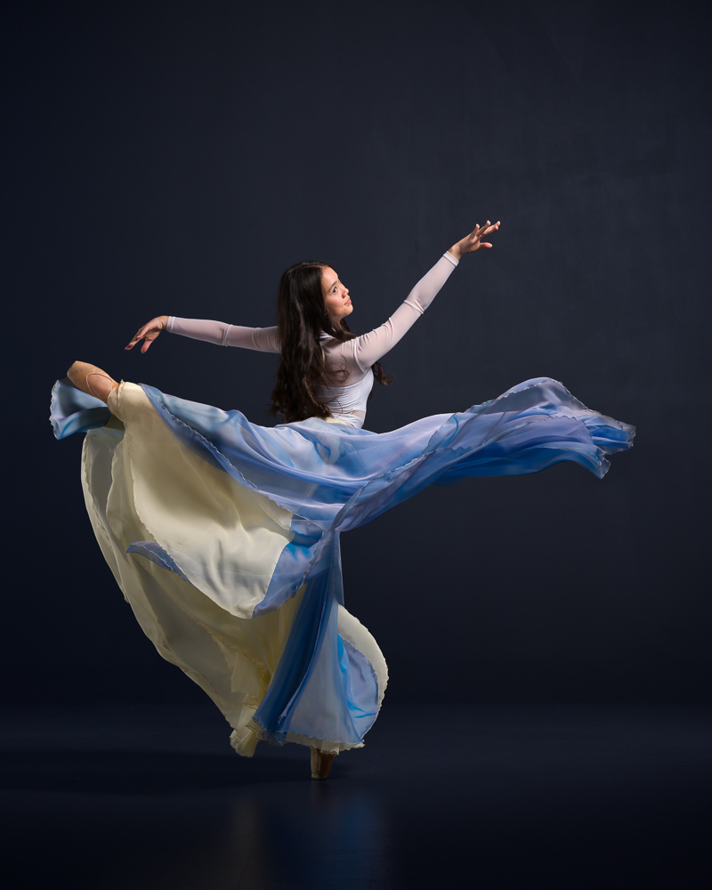 Dancer in arabesque with flowy skirt and lots of forward motion.