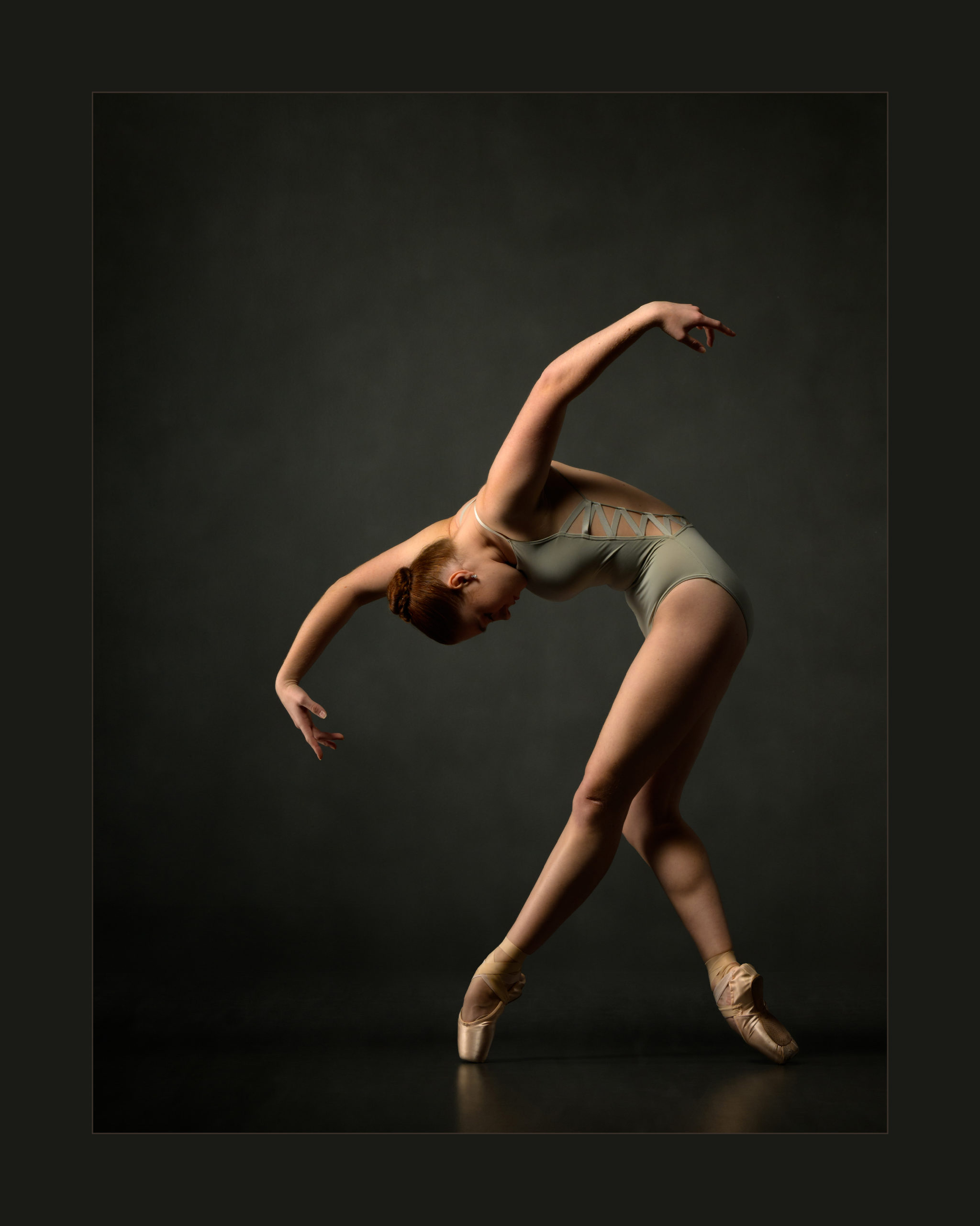 Ballerina in contracted form with arms shaped like wings in profile and front leg of plie fourth shaped as if a talon.