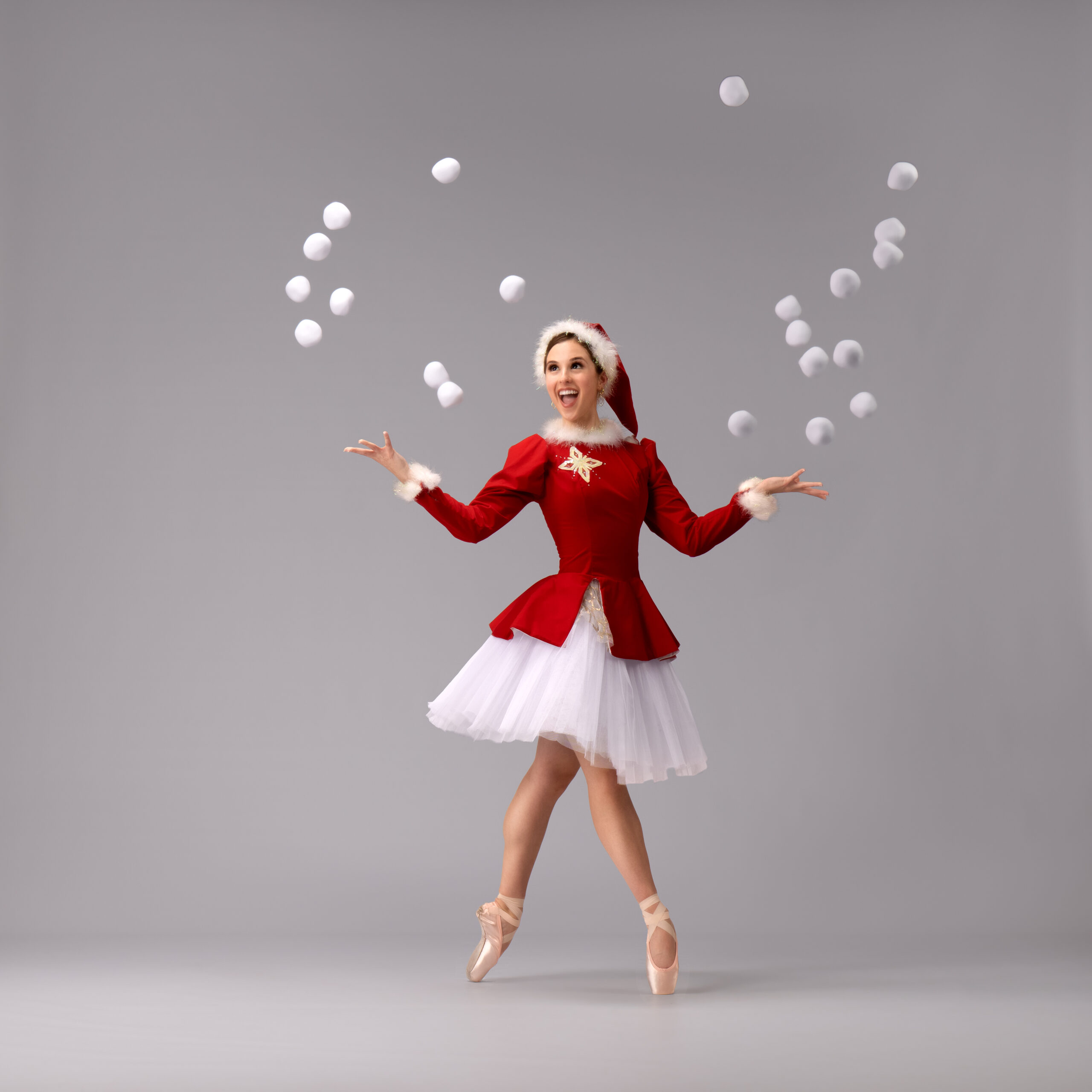 Dancer in santa tutu tossing snow balls in the air with a gleeful smile.